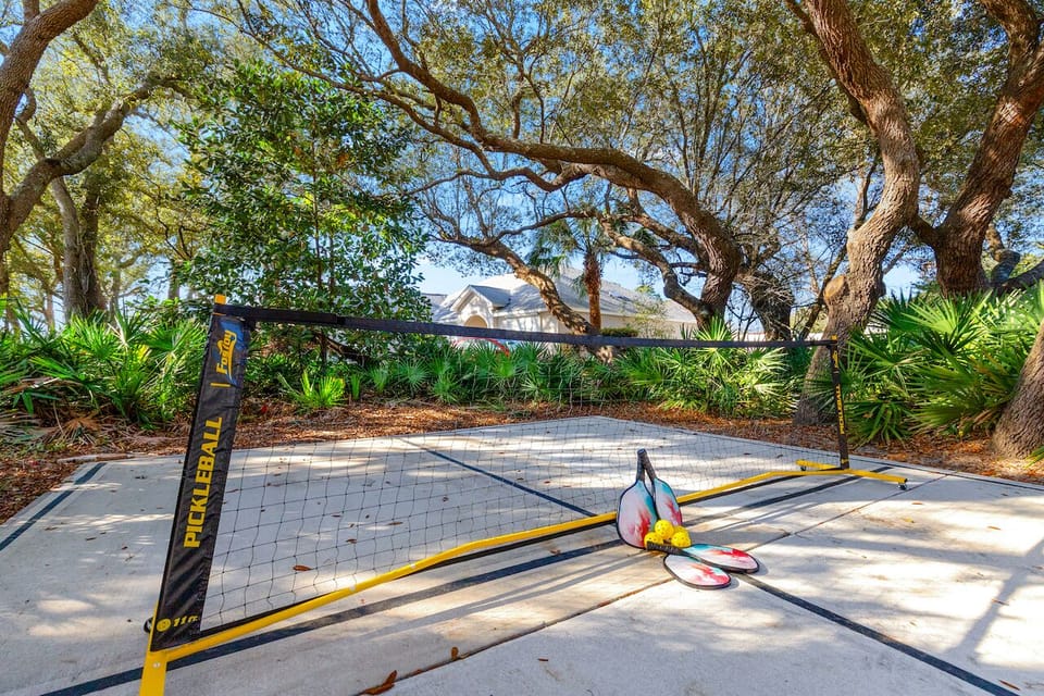 Private outdoor pickleball court under oaks—paddles included
