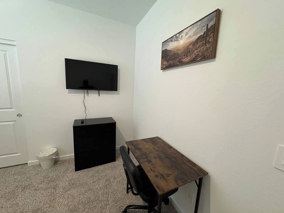 Small bedroom or office with wall TV, cabinet, desk, and chair
