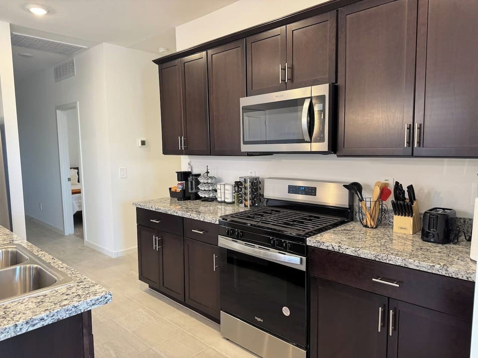 Kitchen wall with stove, microwave, dark cabinets, and counters