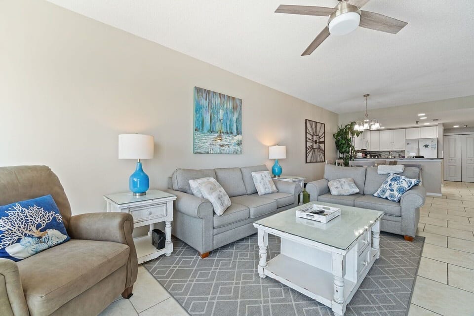 Bright living room with ocean views, cozy seating, and a large TV