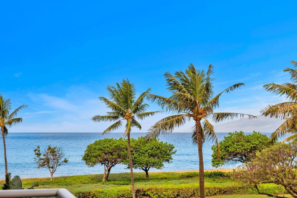 Partial ocean view framed by swaying palms and lush landscaping—your lanai is perfect for morning coffee or sunset drinks. HKH-203