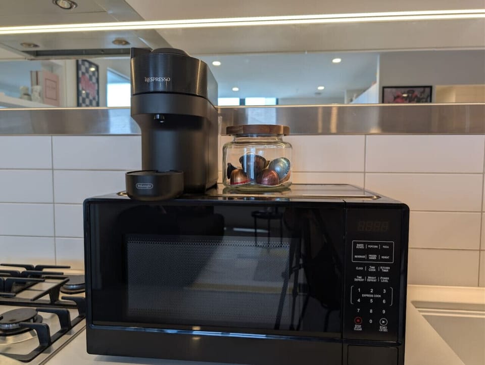 Nespresso machine with a jar of capsules and a microwave, all within easy reach on the kitchen counter. Everything you need to start the morning without stepping outside.