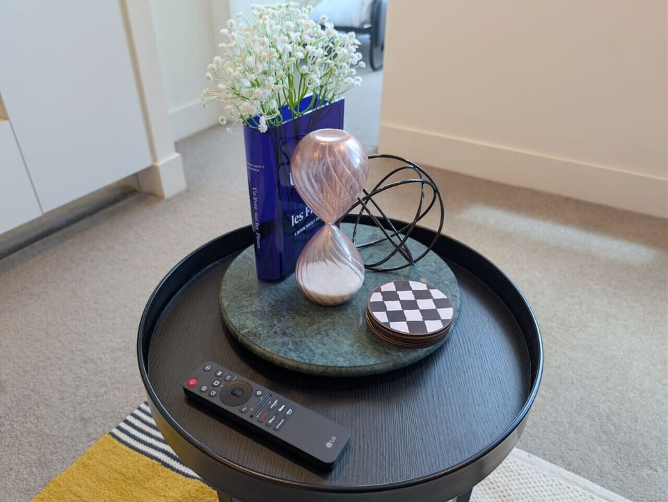 Curated side table styling with fresh florals and decorative accents, keeping the TV remote within easy reach - a small, thoughtful detail for a comfortable stay.