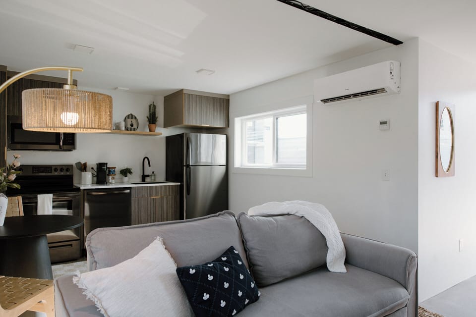 Bright and thoughtfully designed living area featuring stylish coastal décor, comfortable seating, and sweeping windows for plenty of natural light.
