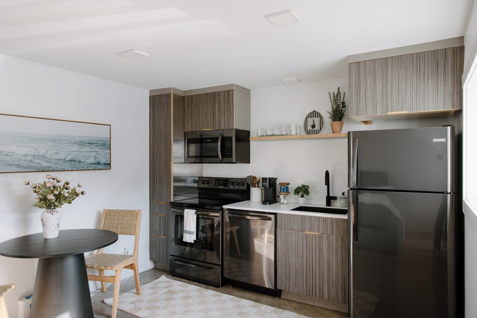 Bright and thoughtfully designed living area featuring stylish coastal décor, comfortable seating, and sweeping windows for plenty of natural light.