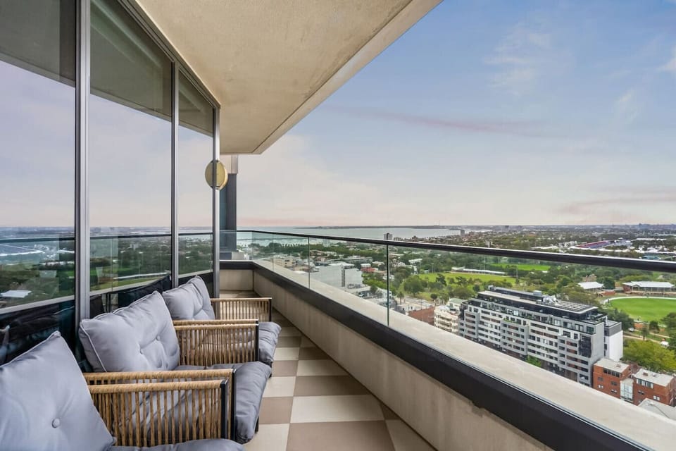 Generous balcony with cushioned rattan chairs and unobstructed views stretching across Port Phillip Bay and Melbourne`s southern suburbs. A genuinely outstanding outdoor space to sit and take it all in at any time of day.
