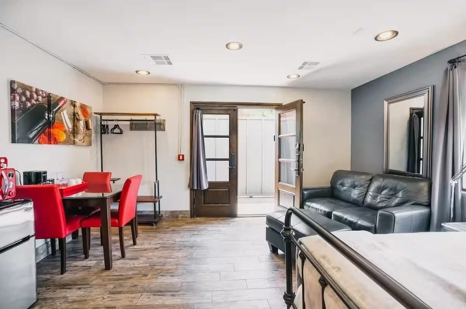 Bright and open bedroom featuring a King bed, smart TV, cozy furnishings, dining area, mini fridge, microwave, and an en-suite bathroom.