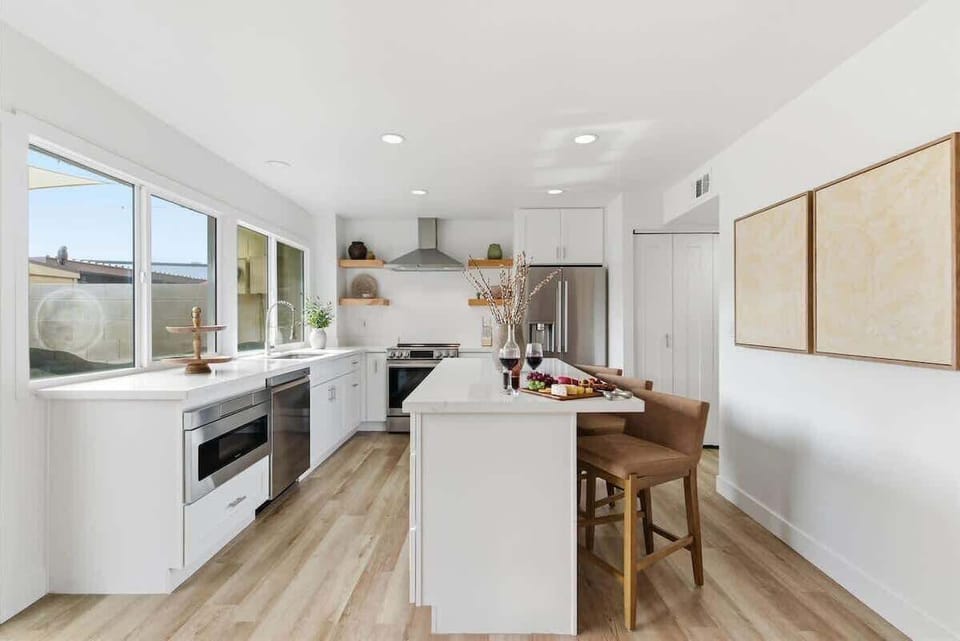 Fully equipped kitchen with stainless steel appliances, bar seating for three, and a coffee bar with a drip coffee maker and a mini fridge.