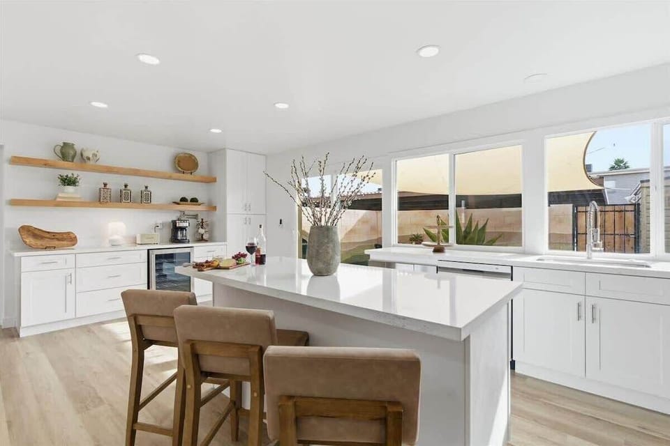 Fully equipped kitchen with stainless steel appliances, bar seating for three, and a coffee bar with a drip coffee maker and a mini fridge.
