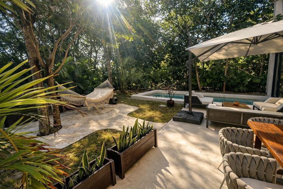 Amplio jardín privado con alberca y área lounge, rodeado de vegetación que brinda total privacidad.