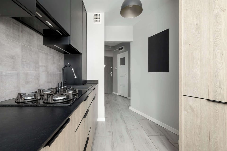 Sleek kitchen corridor with dark countertops, integrated appliances, and clean lines.