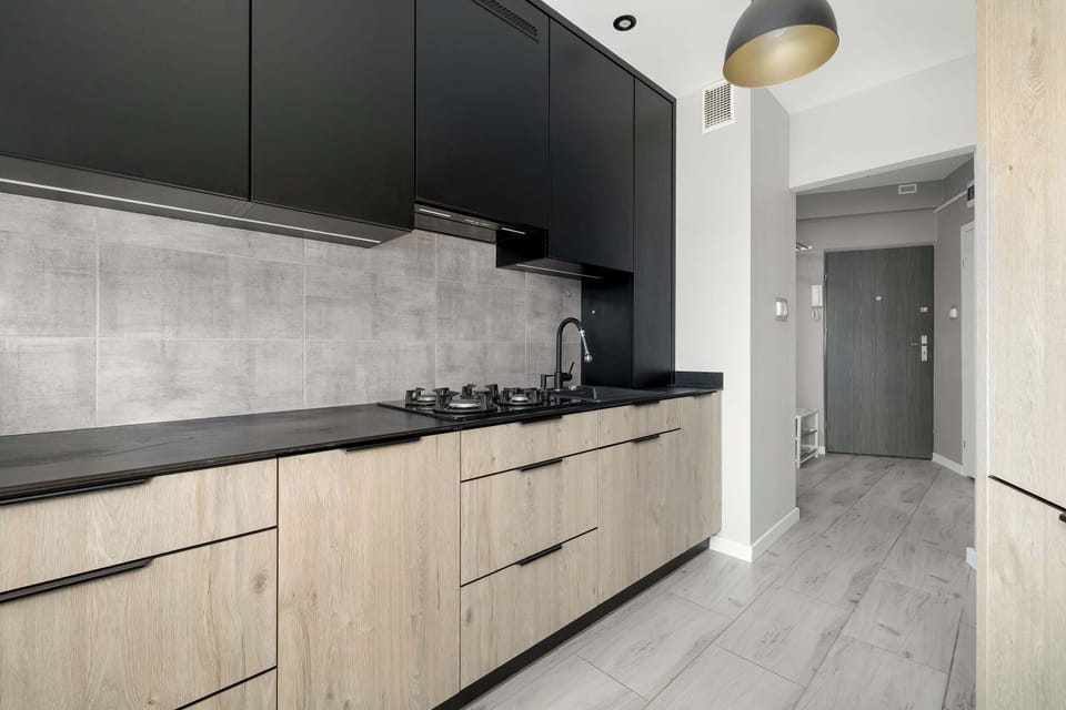 Contemporary kitchen with black and wood cabinetry, bar seating, and clean finishes.