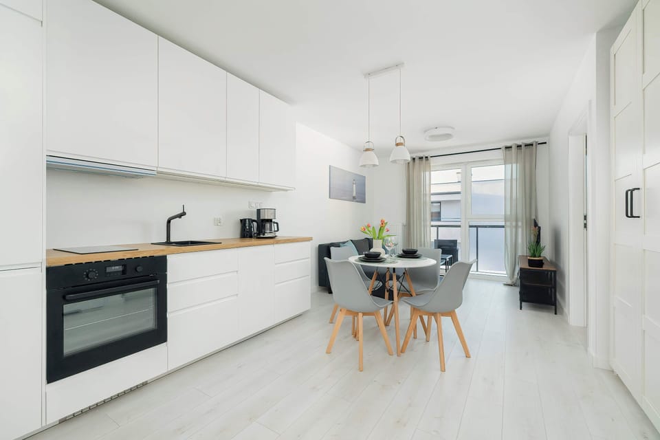 A sleek kitchen featuring built-in appliances and ample counter space. The dining table is visible in the background, creating a cohesive cooking and eating area.