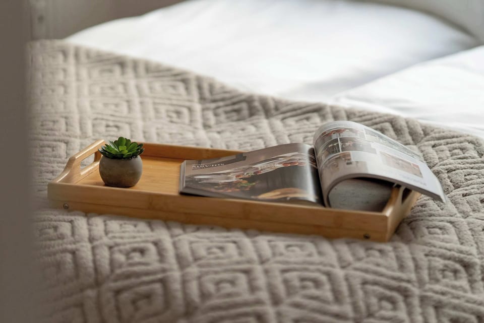 A close-up of a tray placed on the bed with decorative items. Textured bedding adds visual interest. The detail suggests comfort and relaxation.