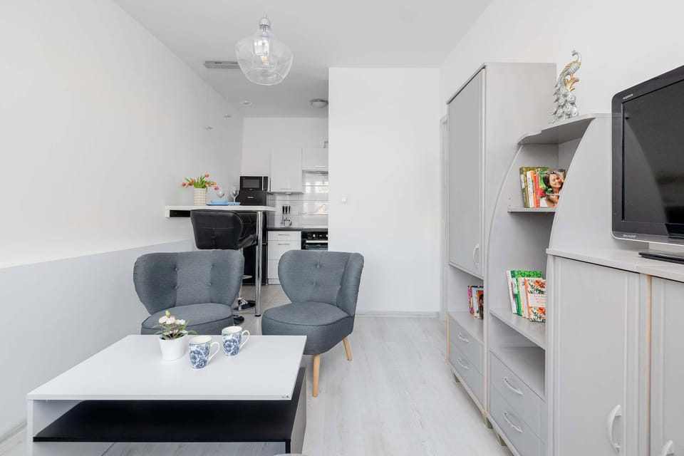 A kitchen view with a dining table set for two. Clean lines and simple decor define the space. Light colors make the area feel open.