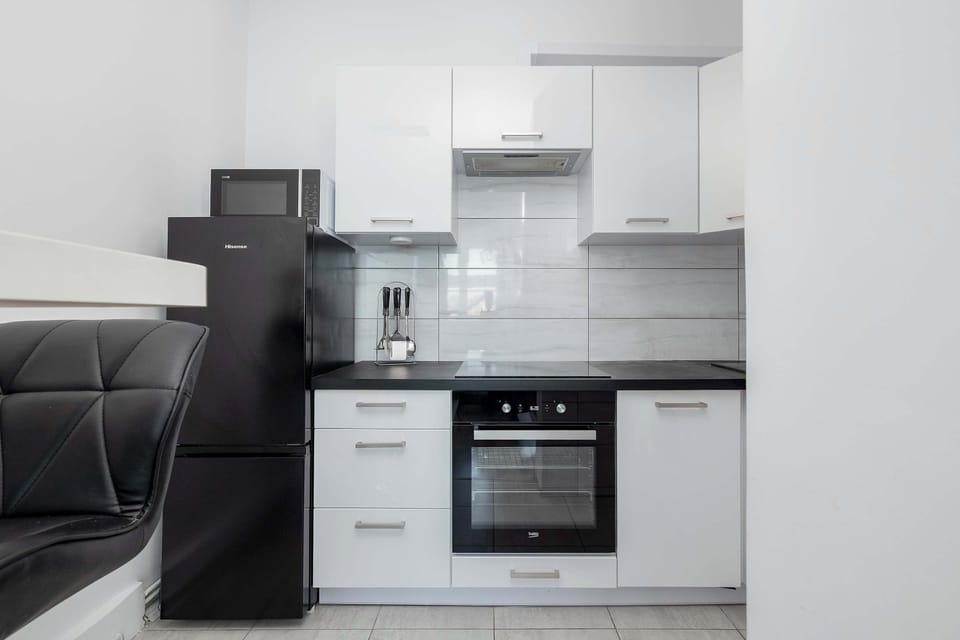 A modern kitchen with white upper cabinets and dark lower cabinets. Built-in appliances create a clean, streamlined look. The layout is compact and functional.