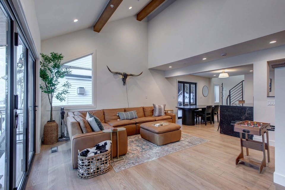 Step into this stunning open-plan living space where warm leather seating and exposed wood beams create your perfect retreat for relaxation and games.