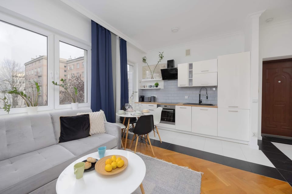 A wider view of the kitchen with a dining table set for a meal. Neutral colors and clean lines dominate the room. The layout appears efficient and inviting.