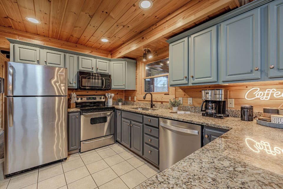 Your fully-equipped kitchen invites culinary adventures with countertops, stainless appliances, and cozy cabin charm beneath warm wood beams.