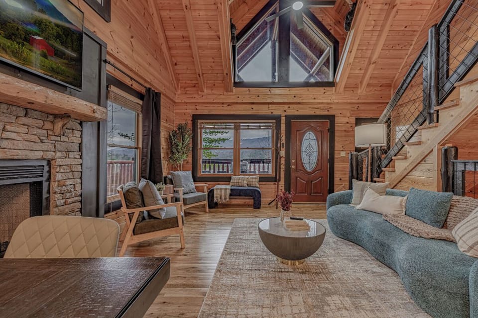 Relax in your cozy mountain cabin living room, featuring warm wood beams, stone fireplace, and panoramic views.