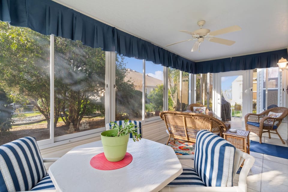 Your bright sunroom offers cheerful blue-striped seating where you'll enjoy morning coffee while watching the garden come alive through floor-to-ceiling windows.