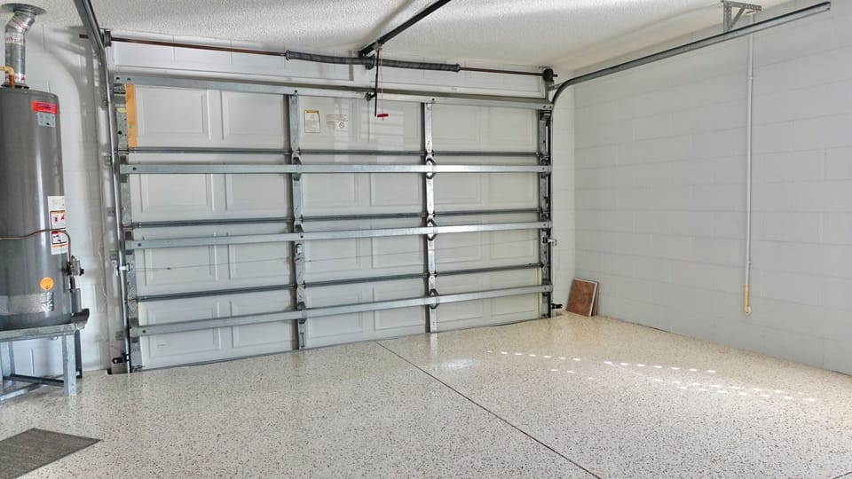 Spacious garage with polished flooring offers secure covered parking for your vehicle and convenient additional storage space.