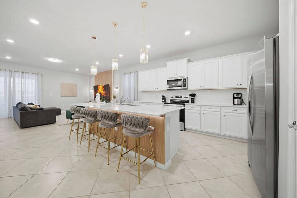 This stylish kitchen combines sleek white cabinetry with a warm wood island for a welcoming feel. Enjoy casual dining on contemporary bar stools while soft natural light streams in through sheer curtains.