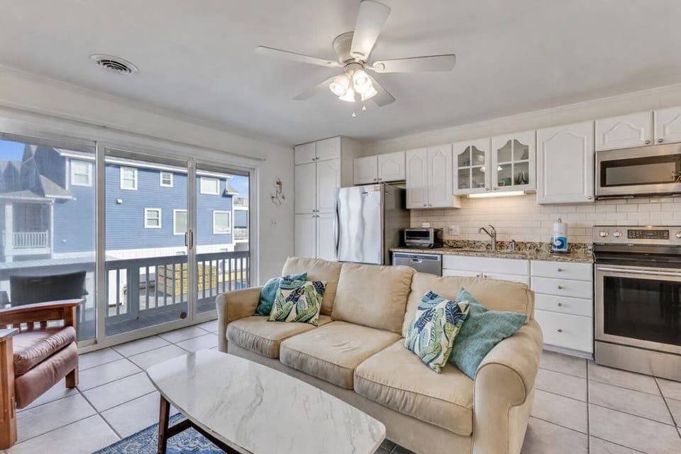 Your bright open-concept space blends comfort with convenience, featuring a fully-equipped kitchen and cozy living area with ocean-themed accents.