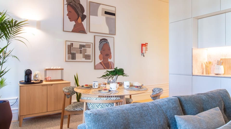 Gather around a handcrafted dining table beneath modern Afro-inspired artwork—this is where Porto mornings begin with style. #ArtfulLiving #PortoRental #CuratedDesign