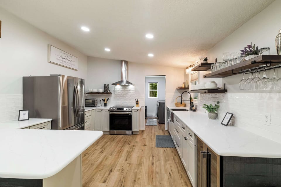 A fully renovated farmhouse kitchen with stainless appliances, quartz countertops, and open shelving — everything your group needs for home-cooked meals in the Poconos.