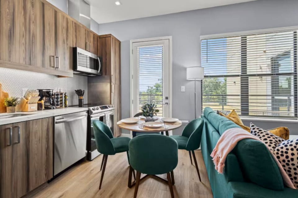 Full Modern Kitchen: Features sleek light-wood cabinetry, granite countertops, and premium stainless steel appliances, including a refrigerator, dishwasher, oven, and microwave.
