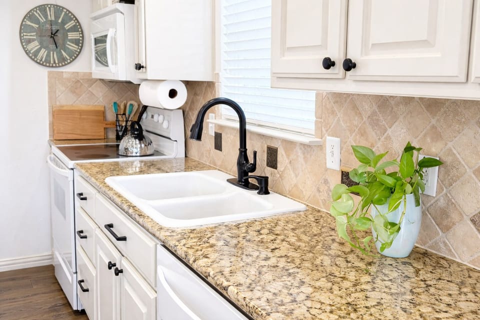 Kitchen with natural stone counters and well-stocked with cookware and appliance