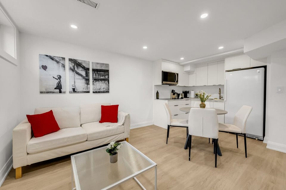 Comfortable and well-lit living room with a large sofa (possibly a pull-out), modern art, and a dining setup nearby. An ideal space to unwind after exploring.