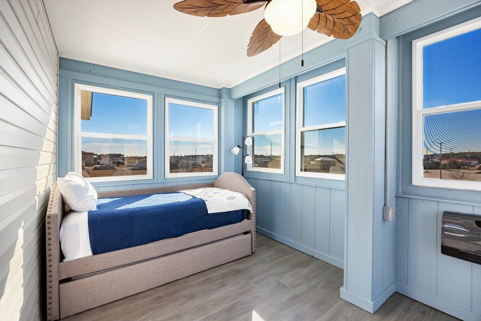 Light-filled sunroom with a daybed and trundle, offering flexible lounging or additional sleeping space.