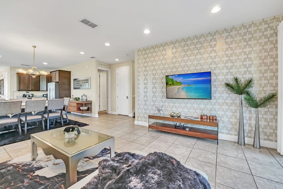 Open-concept living and dining area with modern lighting and patterned accent wall.