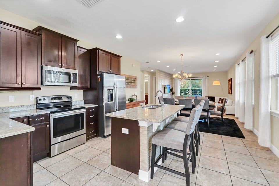 Open kitchen with granite island and stainless steel appliances overlooking the dining and living area