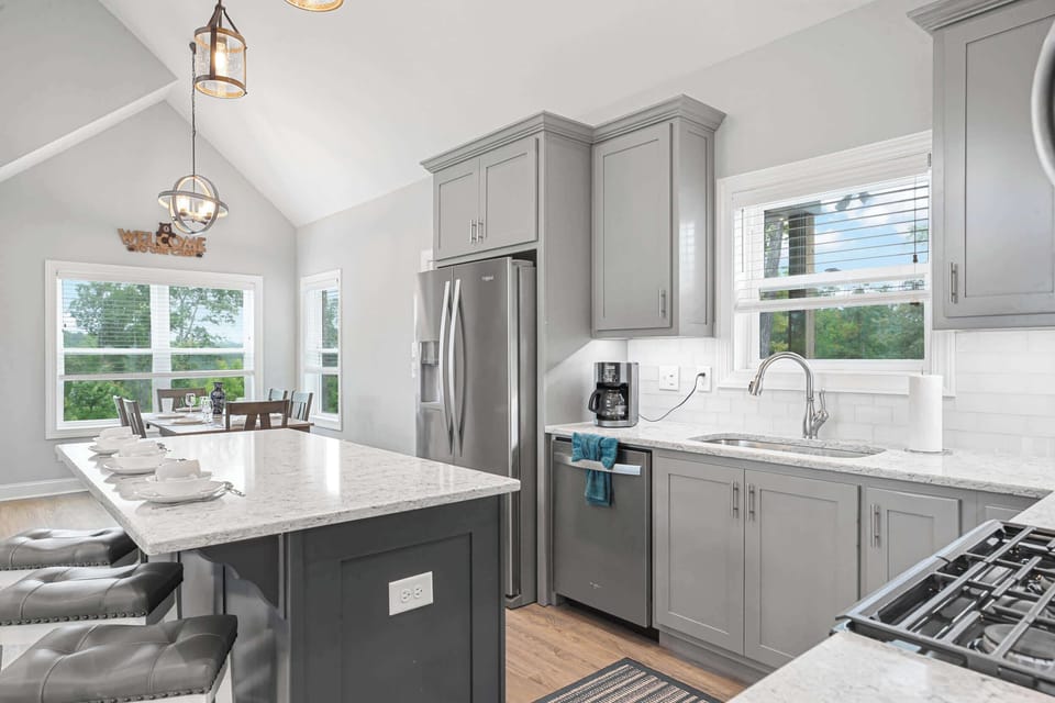 Modern kitchen with gray cabinetry and a large marble island for dining.