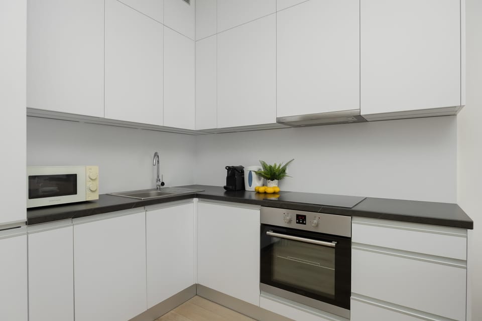 Modern white kitchen with built-in appliances and a clean minimalist design.