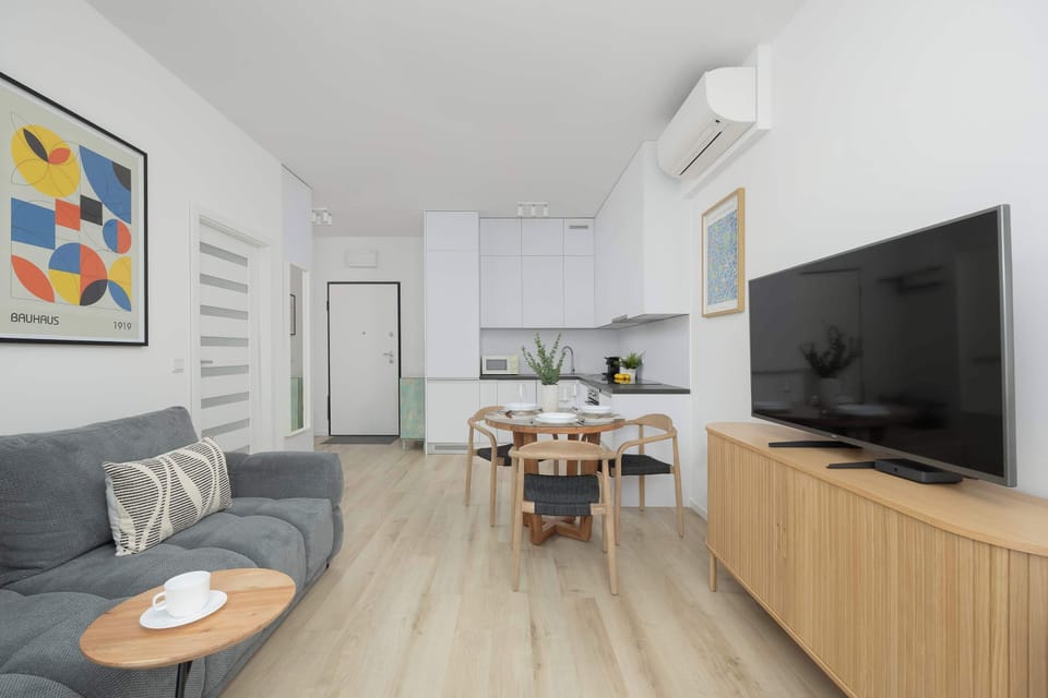 Living room with a comfortable sofa, TV, and dining space in a neutral color palette.