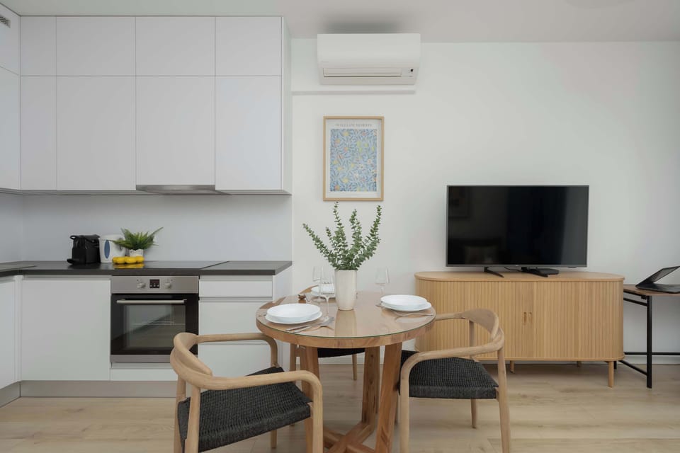 Living room with a comfortable sofa, TV, and dining space in a neutral color palette.