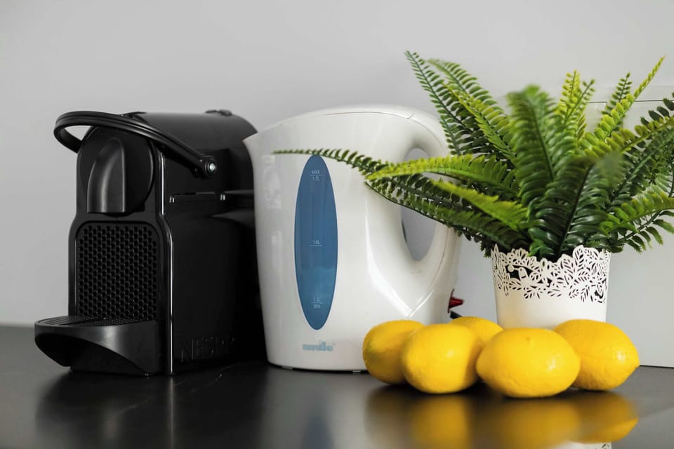 Coffee corner on the countertop with a coffee machine, cups, and fresh lemons.