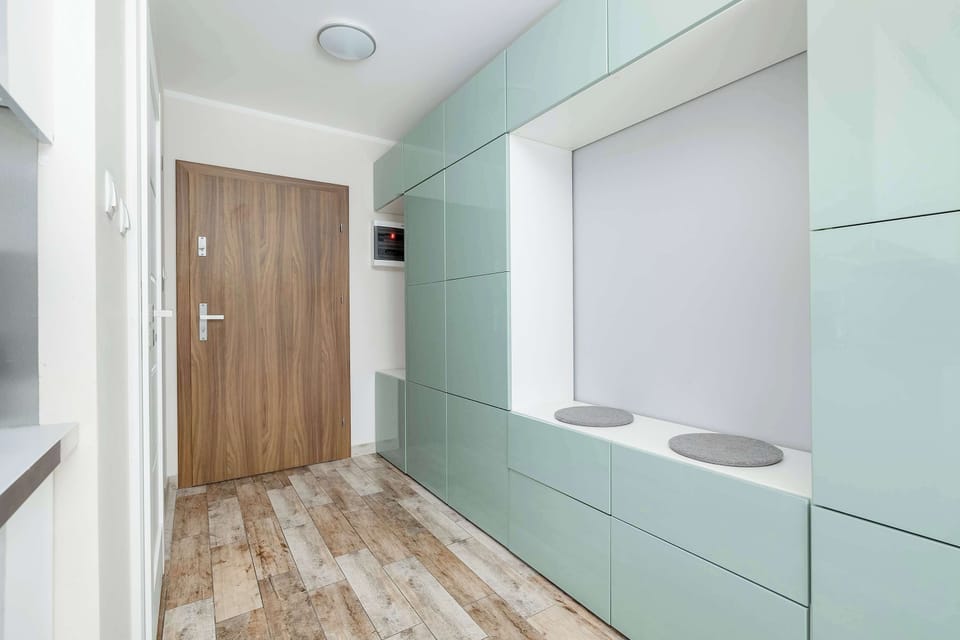 A minimalist hallway with wooden flooring and a built-in storage nook. Clean lines and soft colors make the space feel open and tidy.