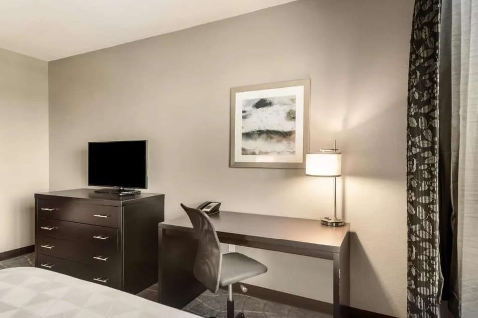 Simple work desk with lamp and TV dresser beside window curtains