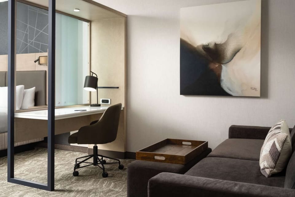 Work desk with soft chair next to couch and abstract wall art