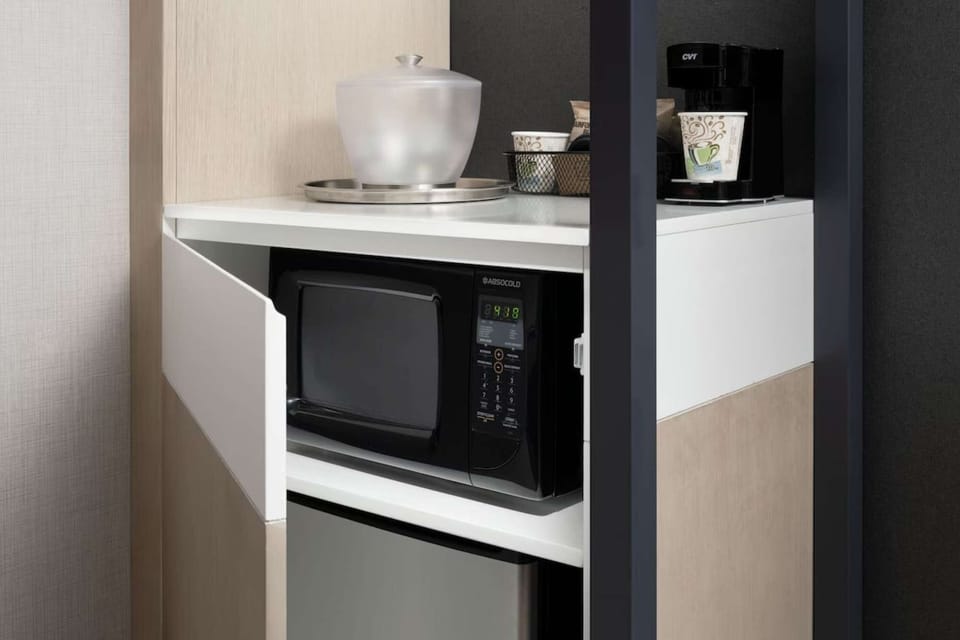 Microwave, mini-fridge, and coffee maker in corner shelf