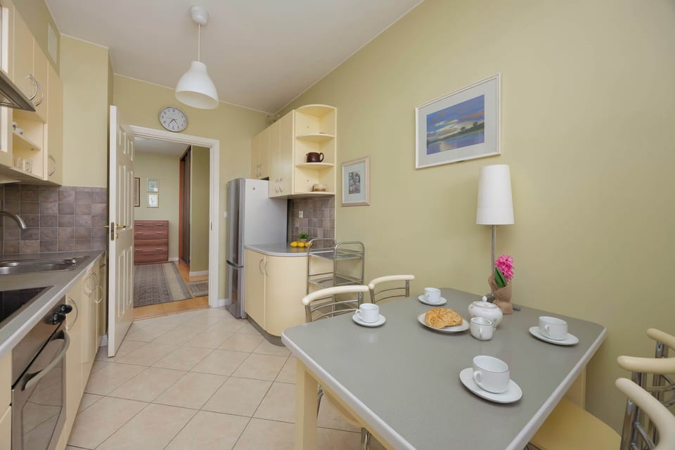 Large kitchen with dining area, light cabinets, tiled surfaces, and practical layout.
