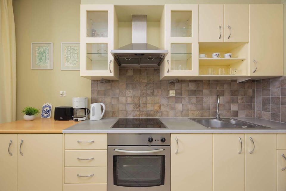 Functional kitchen with light cabinetry, tiled backsplash, built-in oven, and generous storage.