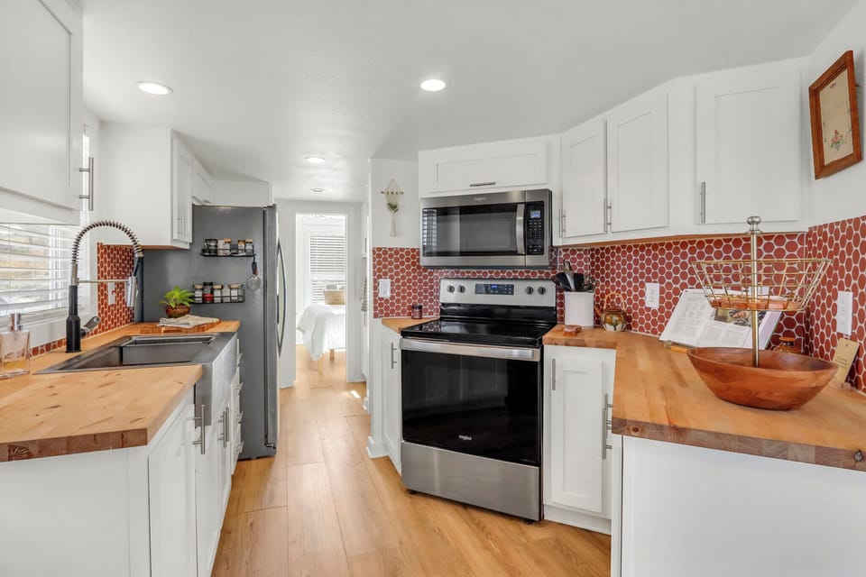Fully equipped kitchen with warm wood countertops, modern appliances, and charming tile backsplash.