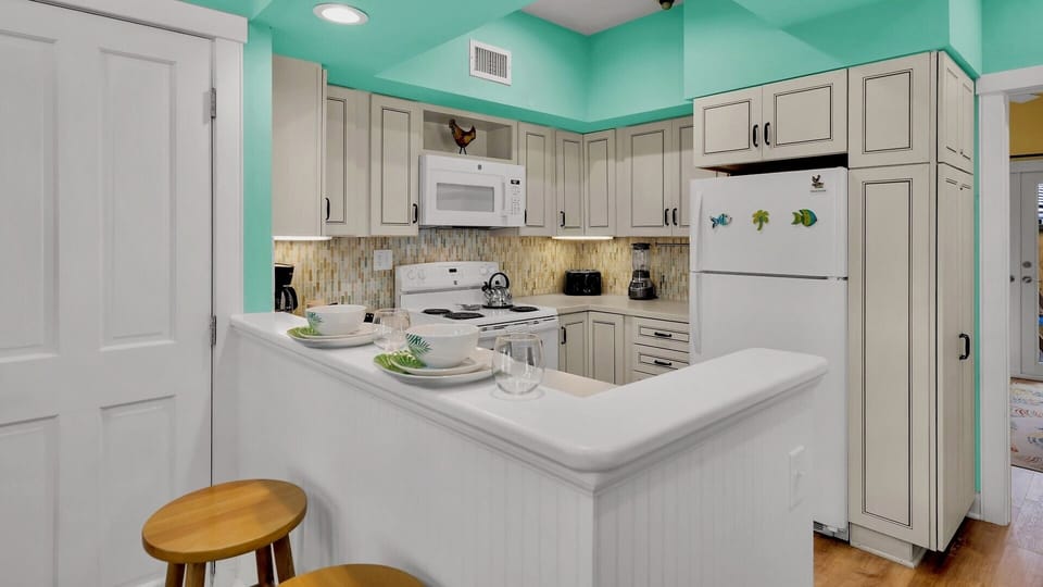 You'll love this bright turquoise kitchen with white cabinets, granite counters, and tropical touches that make cooking feel like vacation.