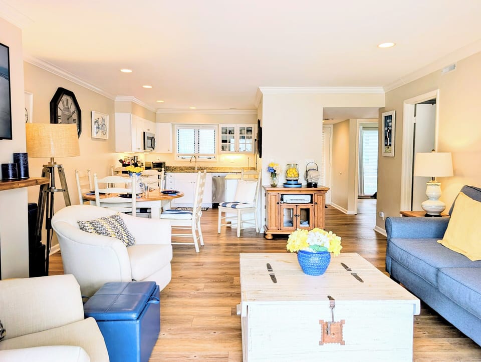 4006 Brighton Trail, sea Colony West living area - Bright and airy living space featuring white coastal furniture, a blue accent sofa, and natural wood flooring.